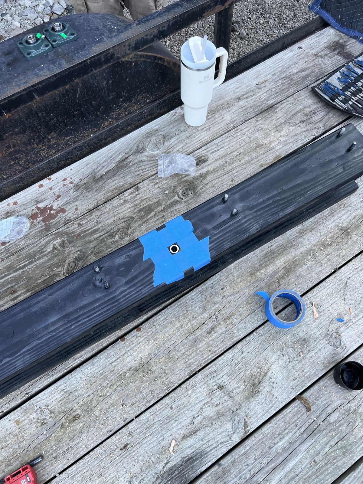 Blue tape marking drill points on a painted beam